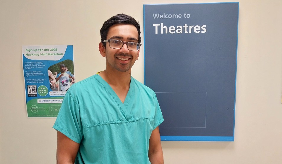 Photo of Dr Anesh Patel smiling in green scrubs, in front of a theatres sign