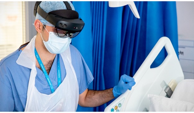 An NHS doctor at St. Mary’s Hospital speaks with a patient on a COVID-19 ward during the pandemic whilst wearing a Microsoft Hololens