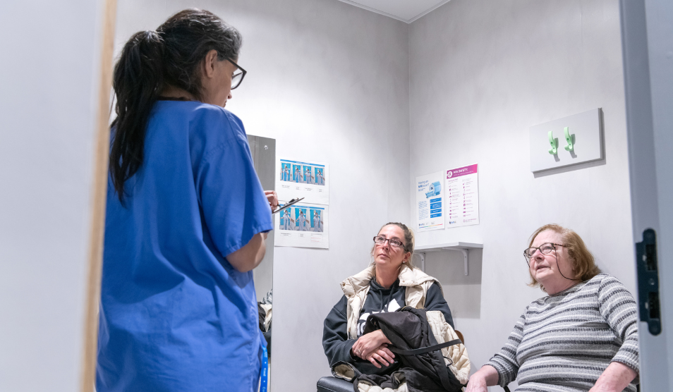 Clinician in scrubs is talking to a patient and her daughter