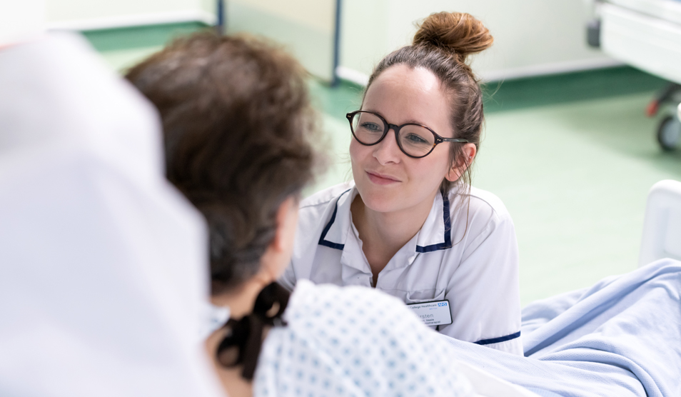 White woman physio on bed with patient 