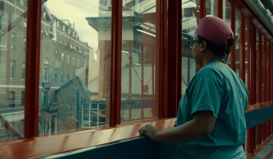 Photo of Maryam Alfa-Wali, trauma surgeon, looking reflectively out of a window at St Mary's Hospital.