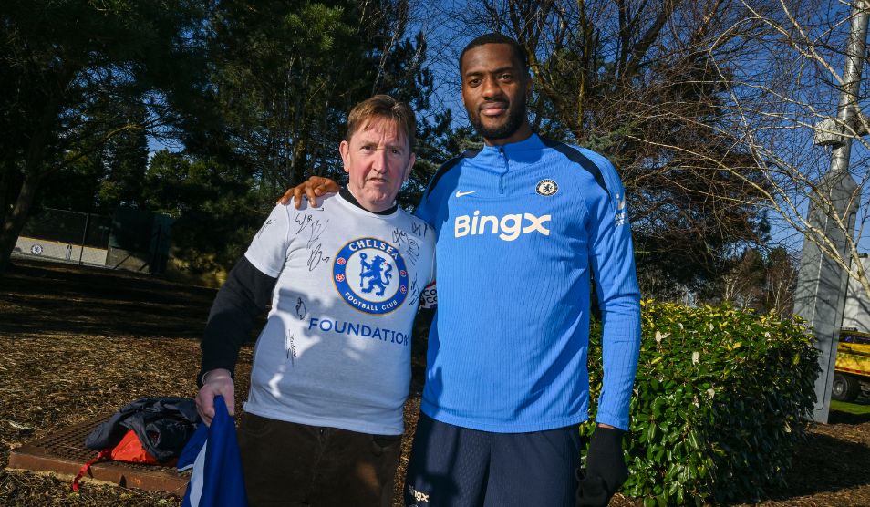 Photo of a former cancer patient standing arm in arm with a member of Chelsea Football Club Foundation.