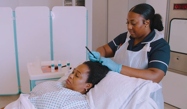 Photo of a nurse styling a patient's hair whilst they are lying in a hospital bed.