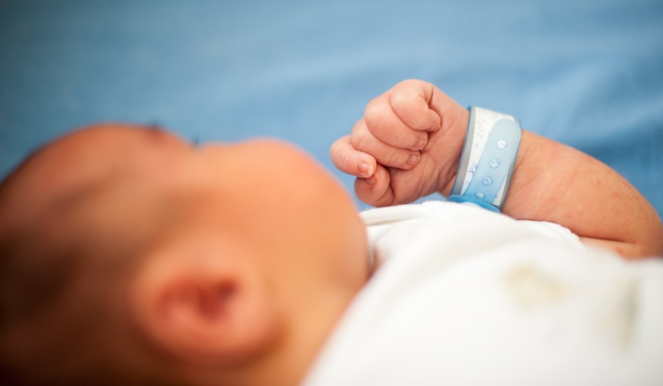Baby laying down wearing a hospital band