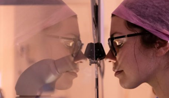 PHoto of clinician lookiing through microscope