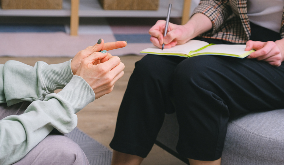 Anonymous female therapist and client sitting in armchairs during session in modern office