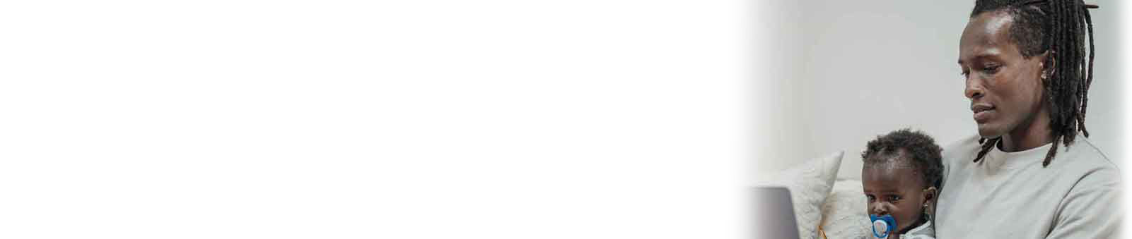 Portrait of father with baby daughter with dummy looking at laptop