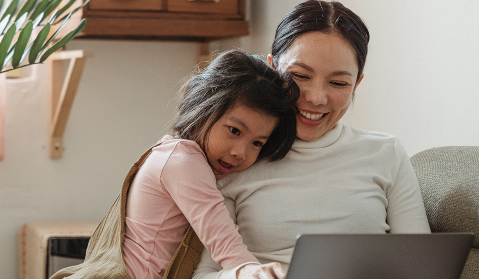 Happy mother using laptop with daughter
