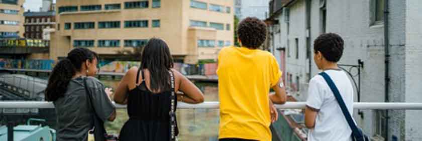 Photo of adolescent girls and boys looking towards a canal